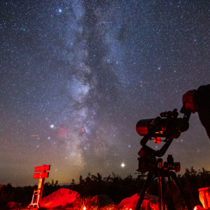 A man views the Milky Way through a telescope.