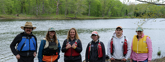 Six people posed in front of a river.