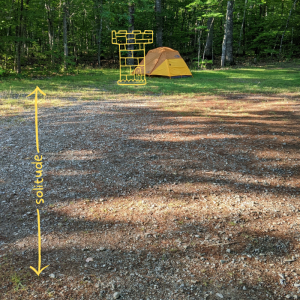 A small tent in a large gravel and grass area with a drawing of a castle turret.