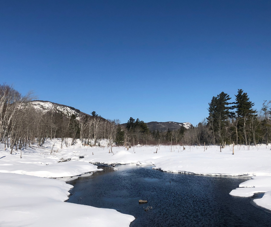 A snowy landscape including a river with open water.