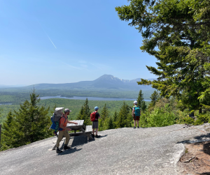 A father and children at a picnic table on a mountaintop.