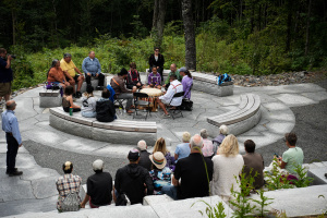 A drumming group performs on an outdoor stone patio for a small crowd