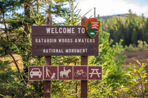 A wooden sign says welcome to Katahdin Woods and Waters Naitonal Monument.