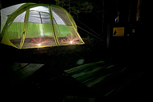 A green tent is lit from within.