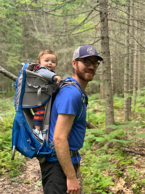 Brian Hinrichs with his son in a backpack in the Maine woods